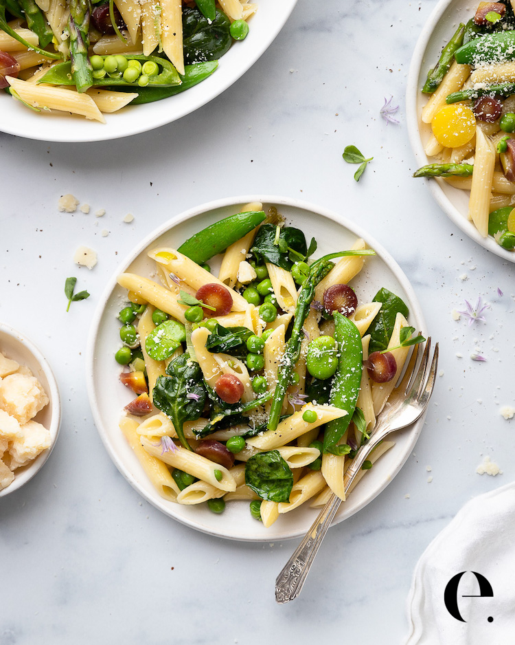 penne pasta with spring vegetables on white plate