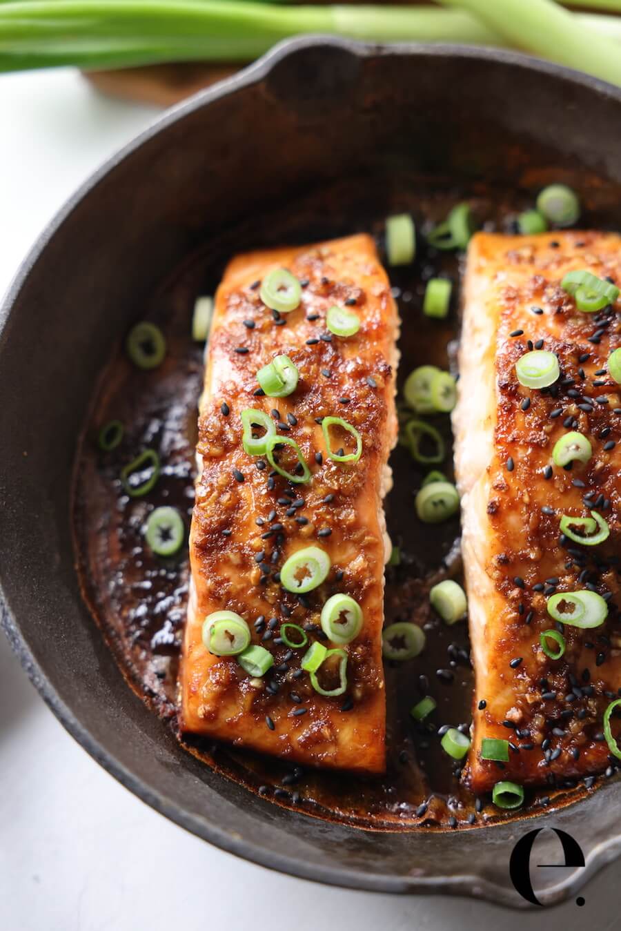 salmon filets on a skillet with green onions