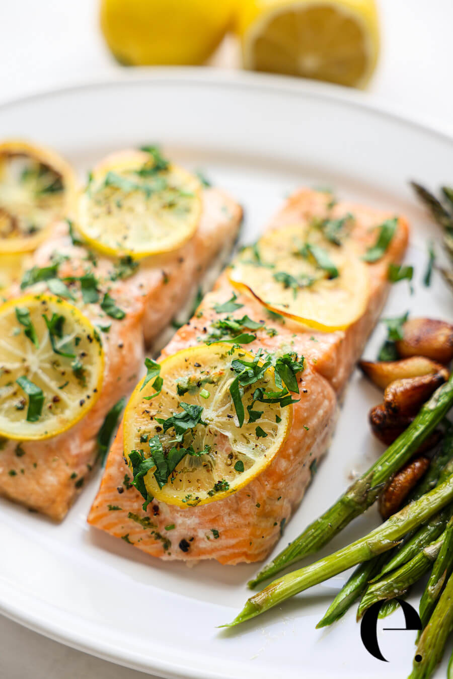 baked salmon with lemon slices and parsley on a plate with green beans