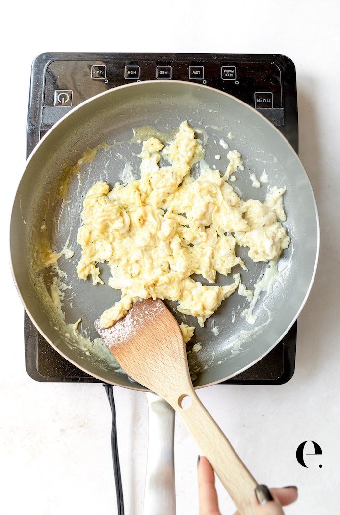 Scrambled eggs in pan with wooden spoon