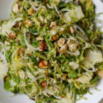 Shaved Brussels sprouts salad recipe by Elizabeth Rider in white bowl with shallot and hazelnuts