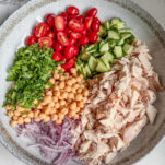 Rotisserie Chicken Salad in Bowl with pulled chicken, chopped cucumber, tomatoes, red onion, garbanzo beans, parsley and Italian dressing