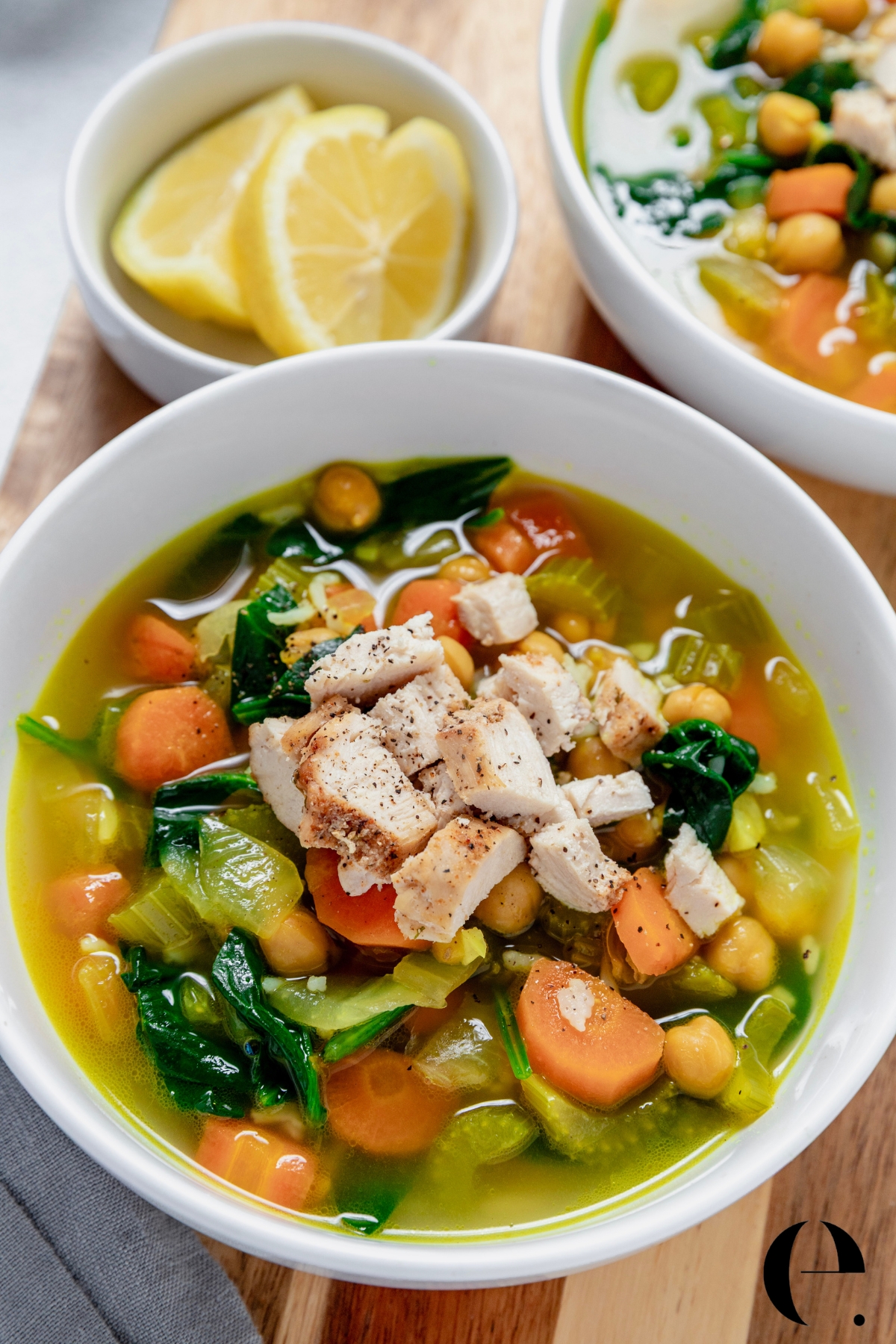 close up of Blue Zones longevity soup in a white bowl with turmeric broth, chickpeas, pasta, leafy greens, carrots
