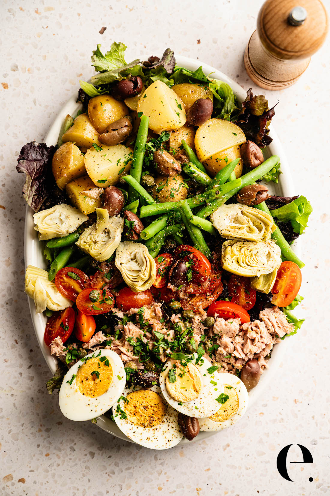 Classic French Nicoise salad recipe with oil-packed tuna, eggs, potatoes, olives, capers, and fresh vegetables by Elizabeth Rider