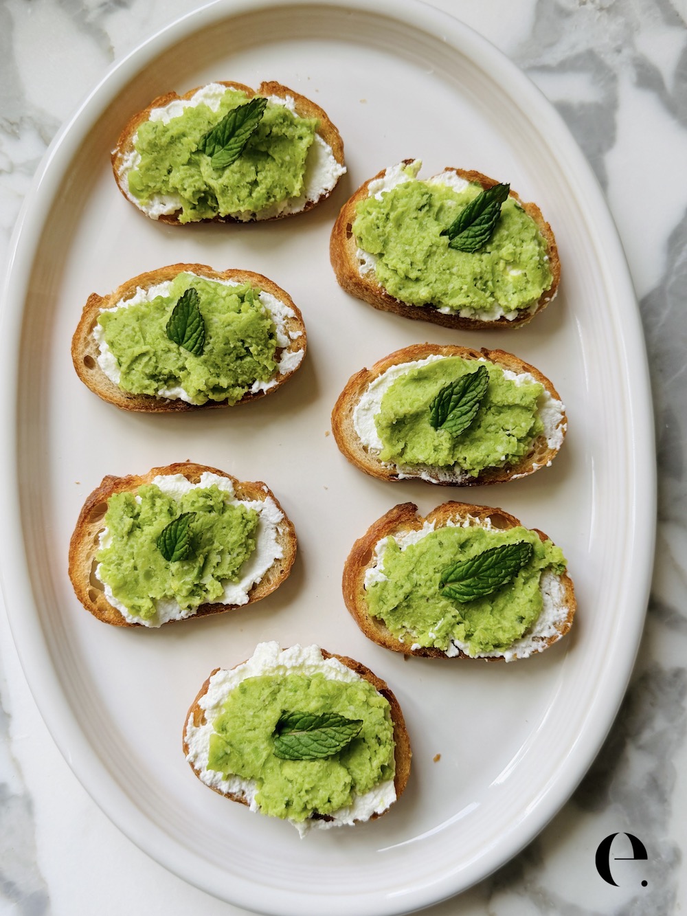 Fava Bean Crostini with Ricotta on white plate by Mint Elizabeth Rider