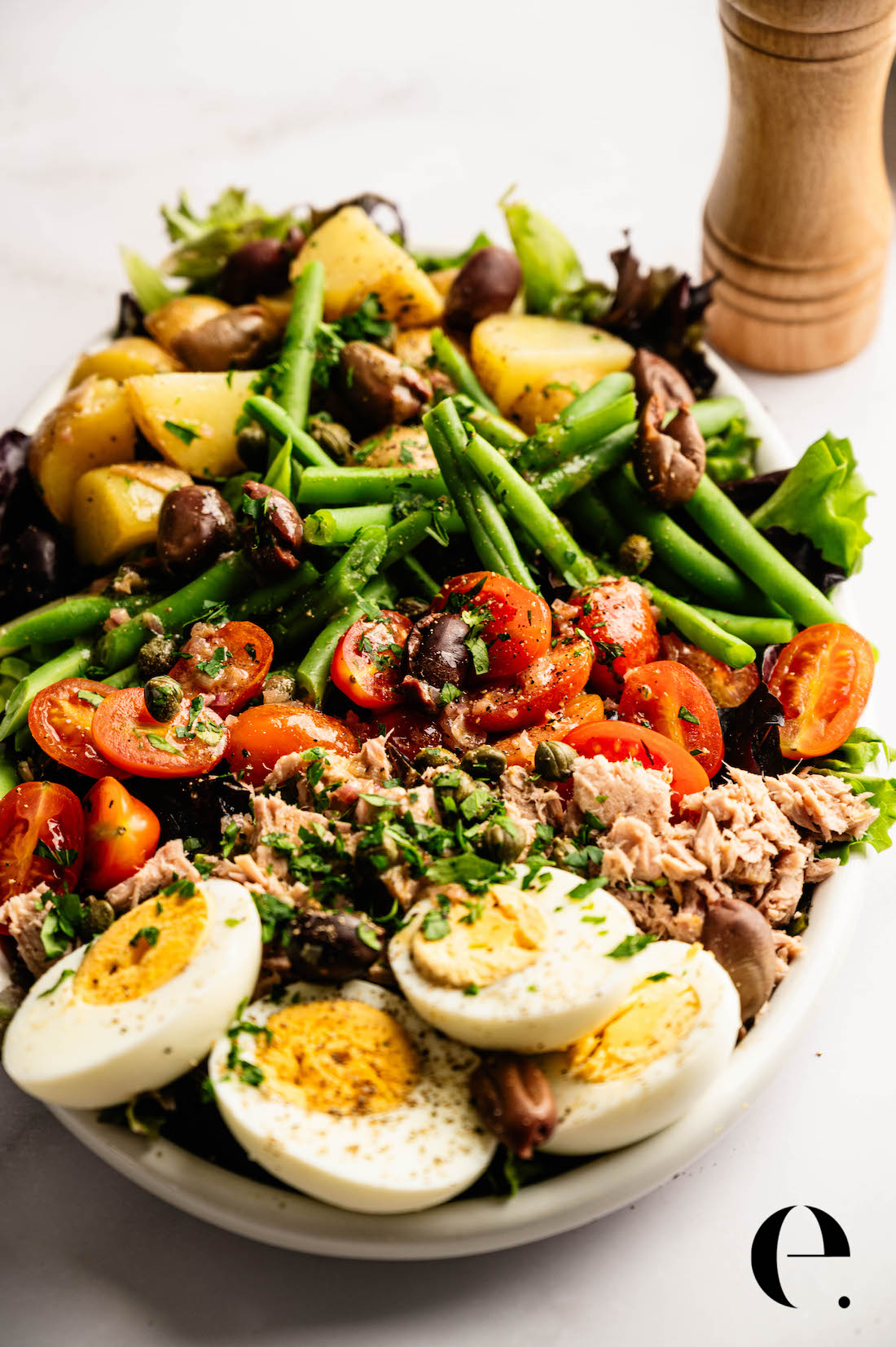 Nicoise Salad Recipe by Elizabeth Rider Nicoise salad with tuna, jammy eggs, potatoes, green beans, olives, and Dijon vinaigrette on a serving platter