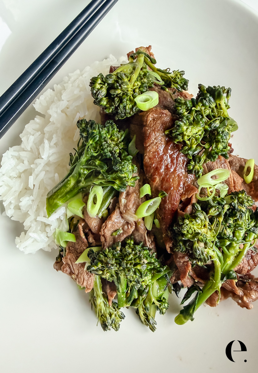 Umami beef with broccoli served over white rice on a plate with black chopsticks