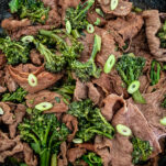 Umami beef with broccolini and green onions finished in a cast-iron skillet by Elizabeth Rider
