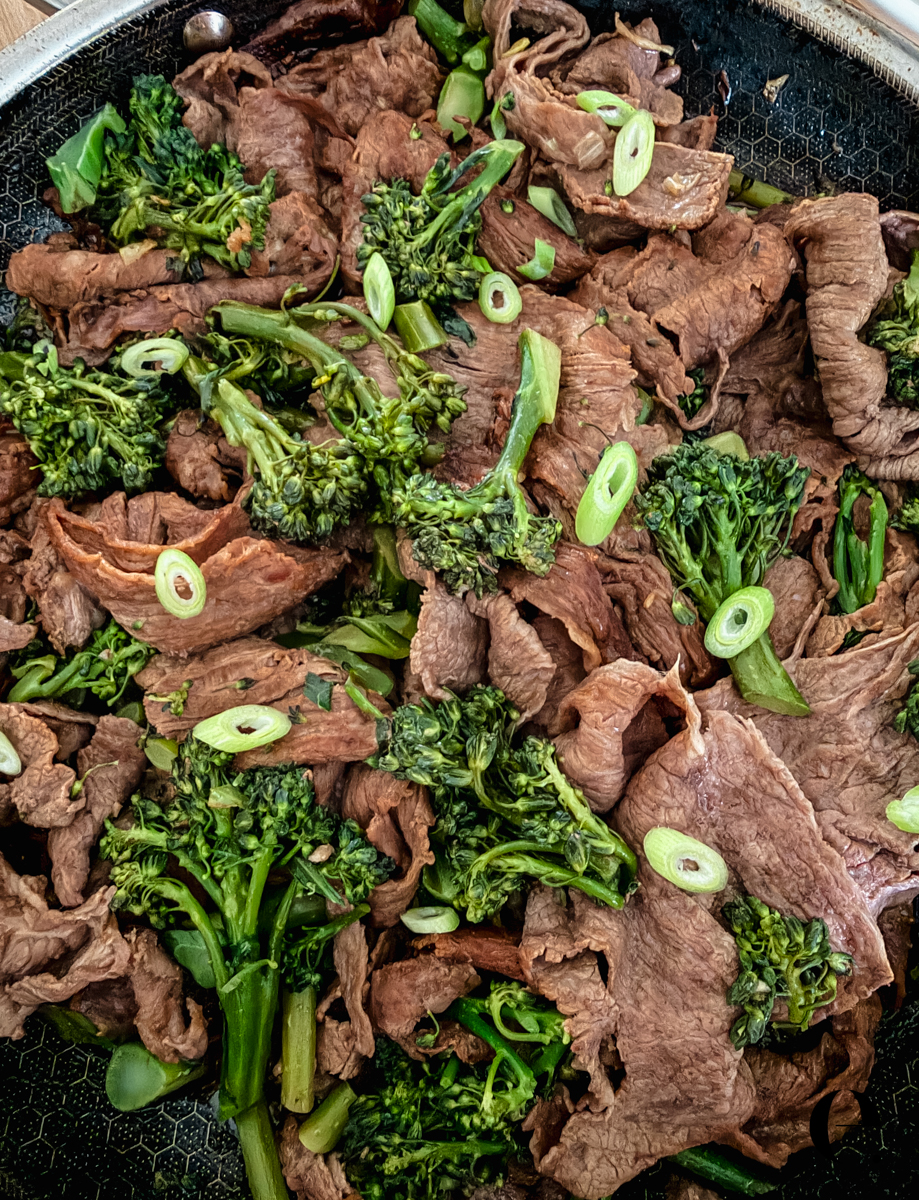 Umami beef with broccolini and green onions finished in a cast-iron skillet by Elizabeth Rider