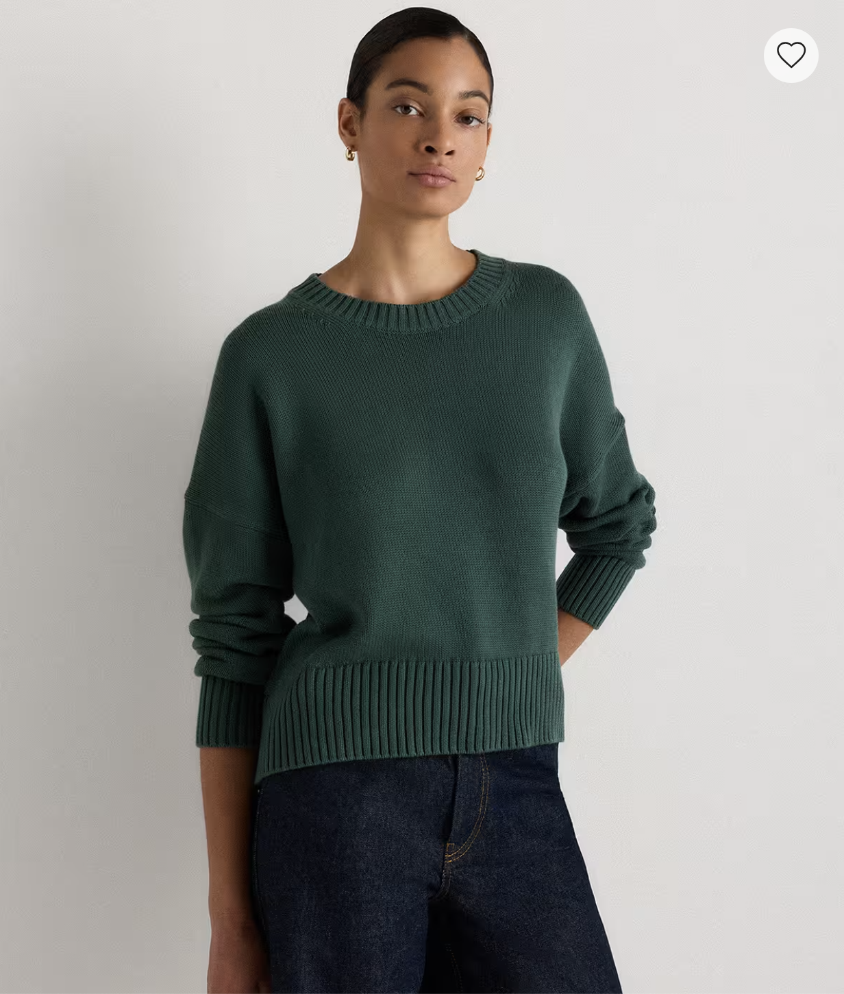Model wearing the Quince Organic Cotton Boyfriend Crew Sweater in dark green with dark-wash jeans.