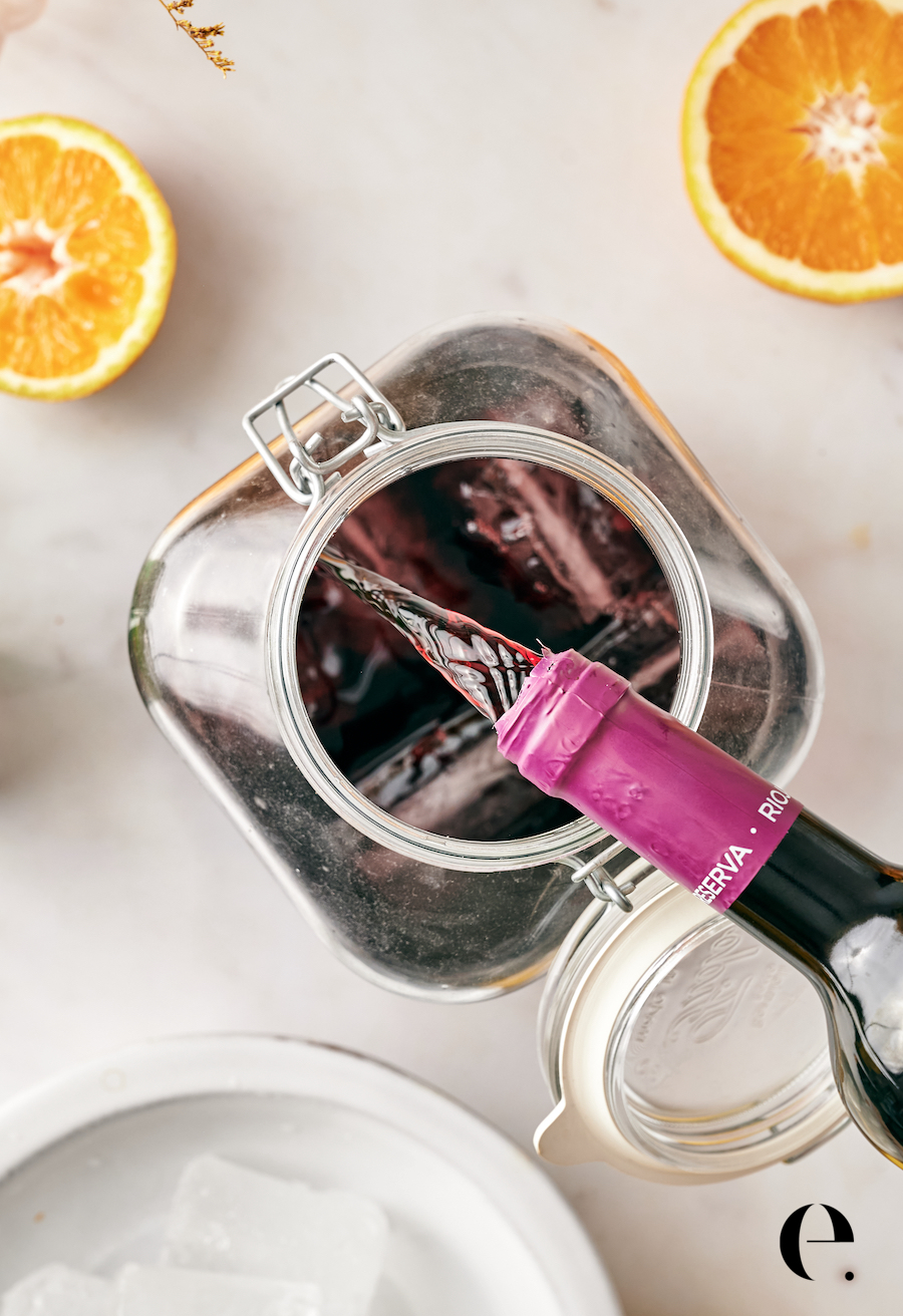 Pouring red wine into a glass pitcher filled with ice to make tinto de verano