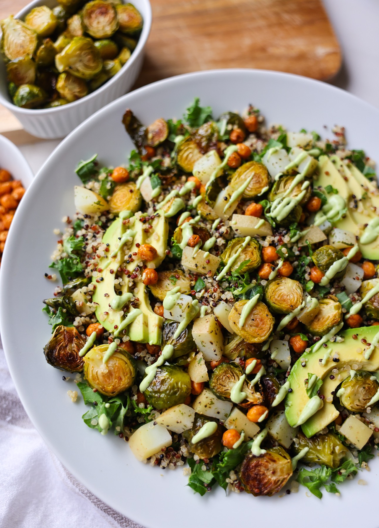 Close-up of a roasted Brussels sprouts quinoa bowl drizzled with creamy green creamy avocado dressing