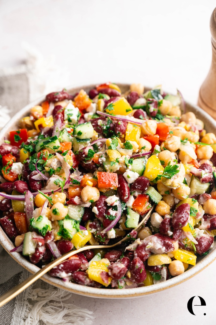 Ingredients for dense bean salad including canned chickpeas, kidney beans, bell peppers, cucumber, red onion, olives, and feta