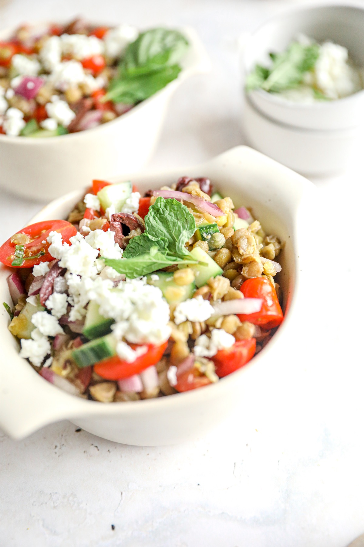 Two bowls of Mediterranean green lentil salad with feta, tomatoes, cucumber and mint