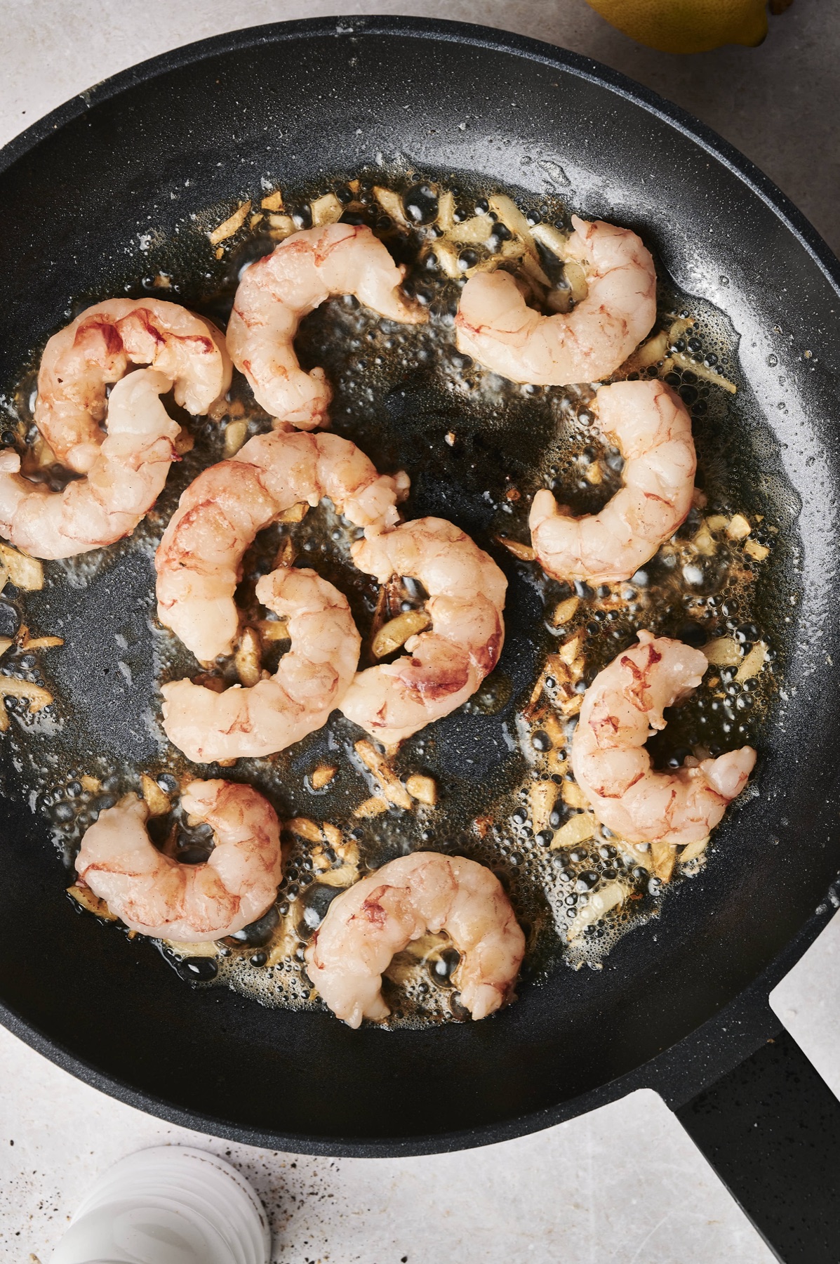 Shrimp searing in garlic butter in a black skillet