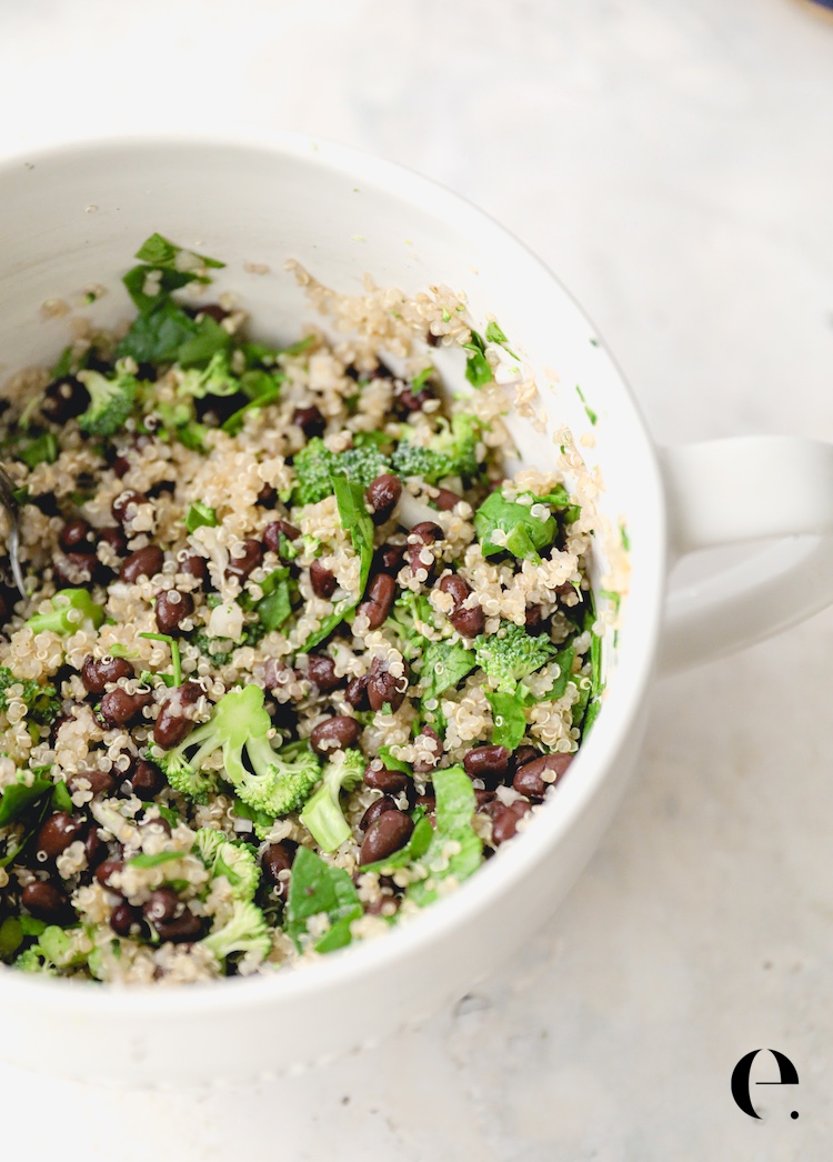 Quinoa, black beans, broccoli and spinach in a white mixing bowl for quinoa stuffed peppers