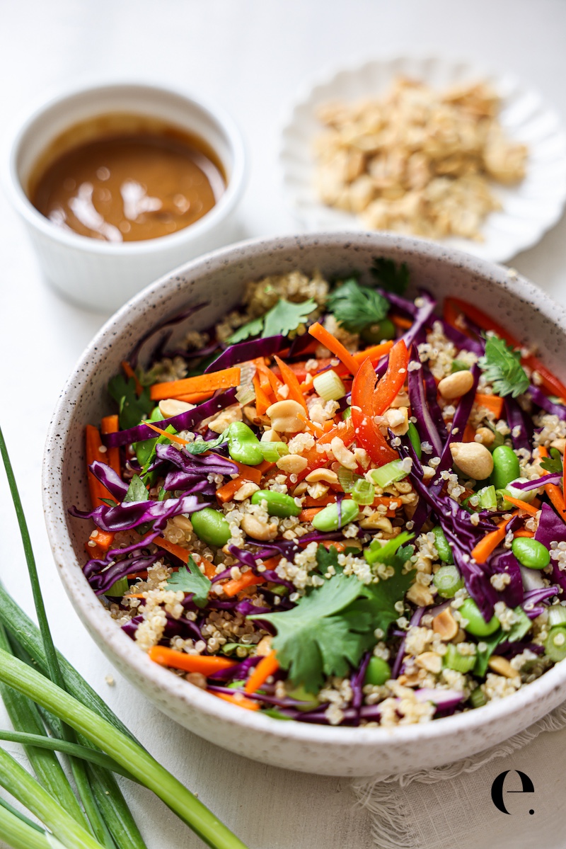 Thai peanut quinoa salad with a small bowl of peanut sauce and roasted peanuts